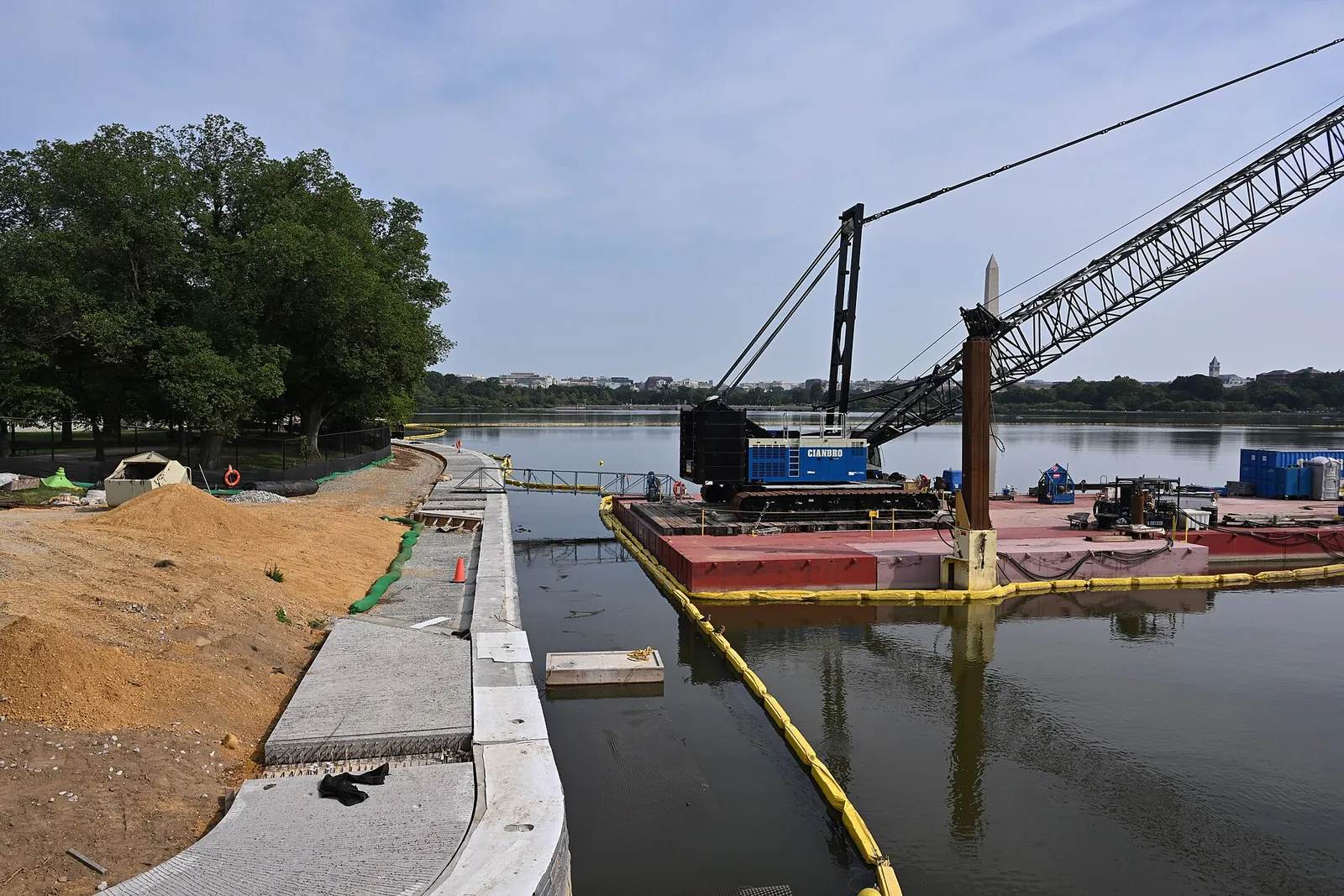 Crane barge moored beside a seawall under construction, with its new concrete cap