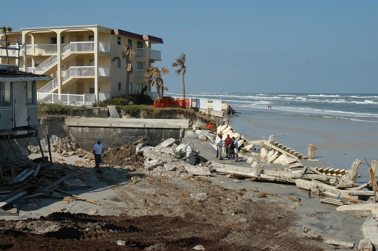 Destroyed concrete seawall and eroded ground below a beachfront condominium after a hurricane